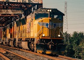A Union Pacific freight train crossing an industrial bridge against a clear sky backdrop.